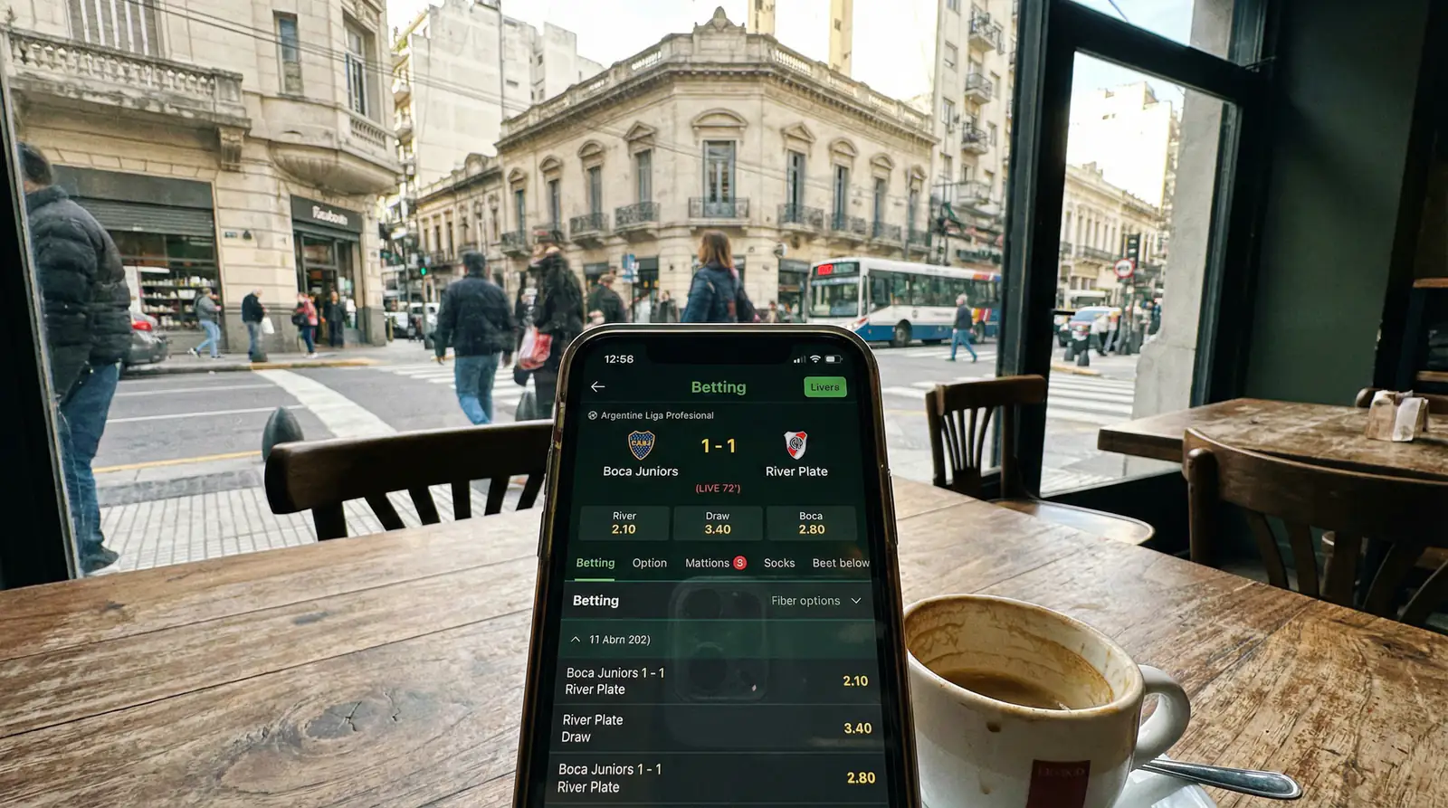 Celular mostrando interfaz de apuestas en vivo con partido de fútbol argentino